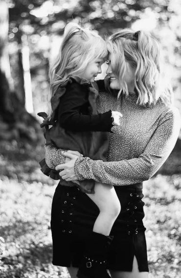 A mother lovingly holding her daughter outdoors, sharing a joyful moment.