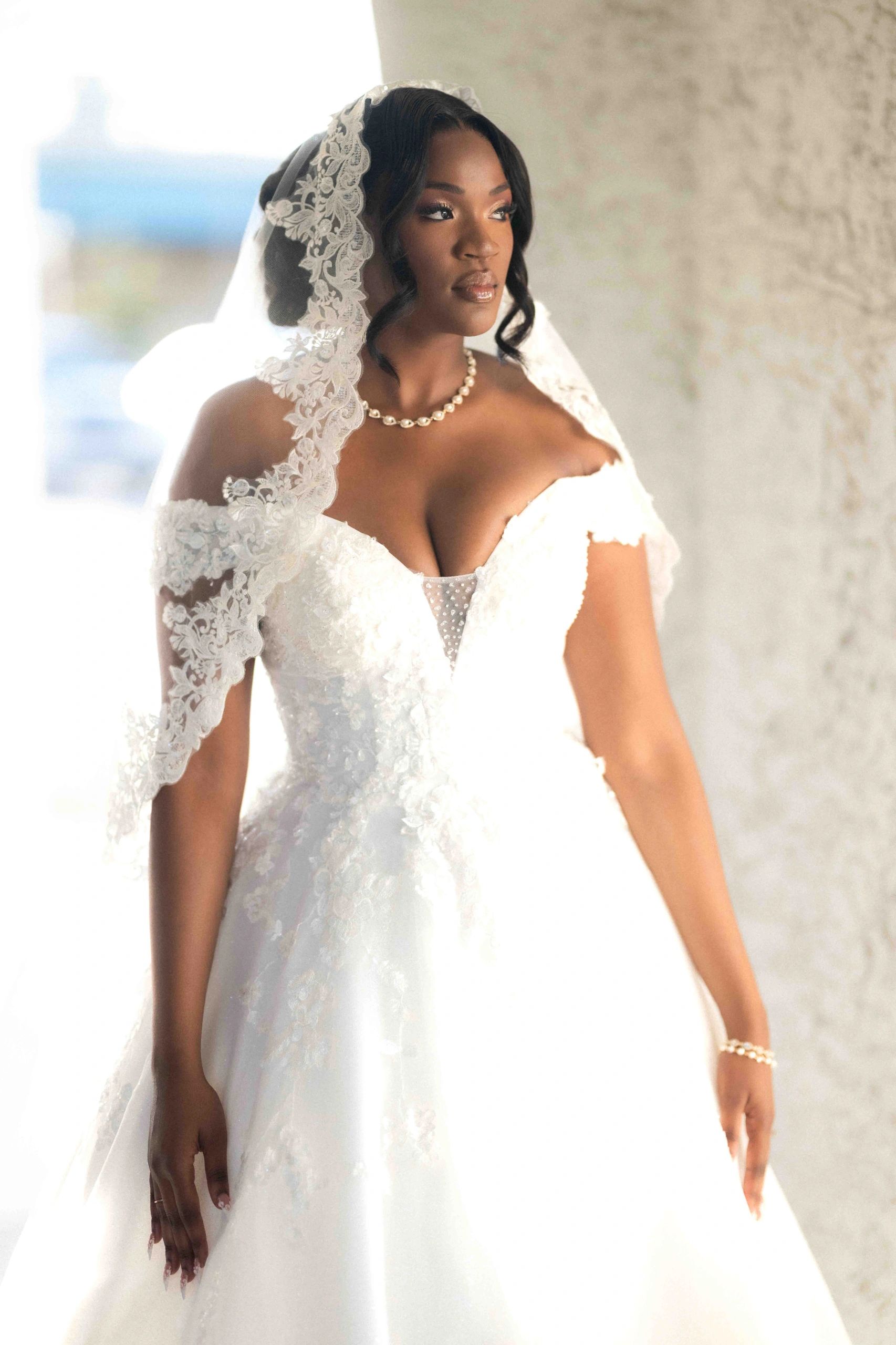 A bride in a white lace wedding dress and veil.