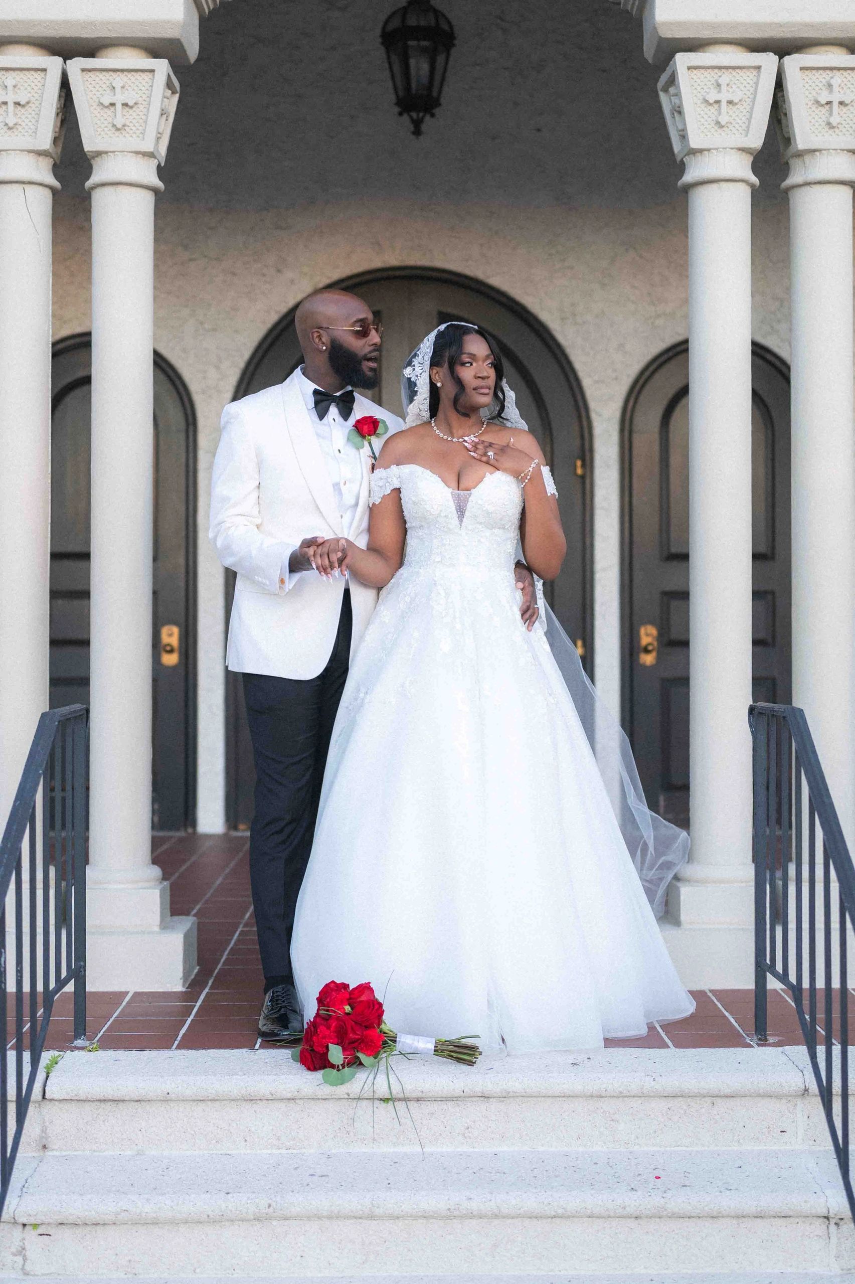 Bride and groom in wedding attire standing on steps.