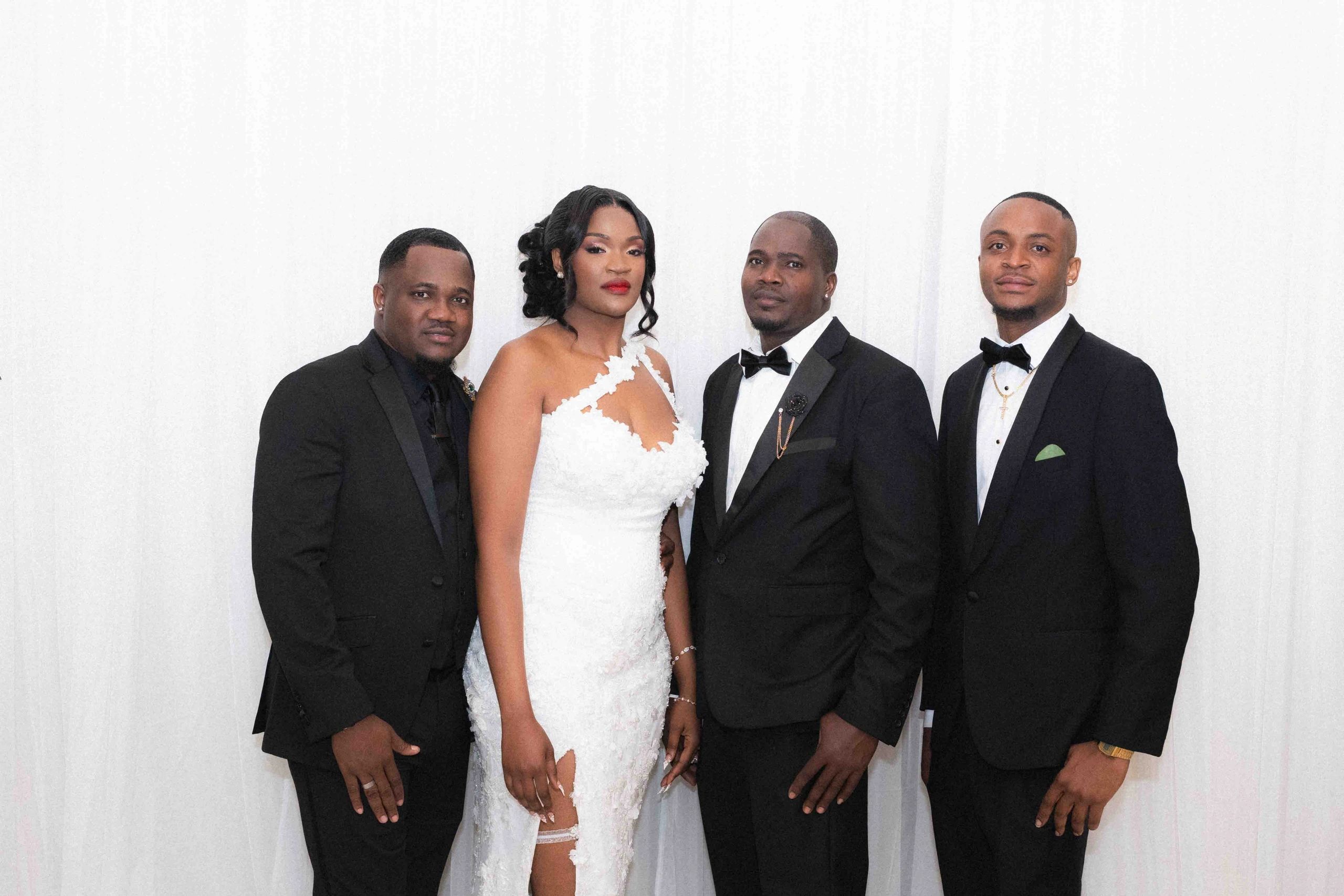 A bride in a white dress with three men in tuxedos.