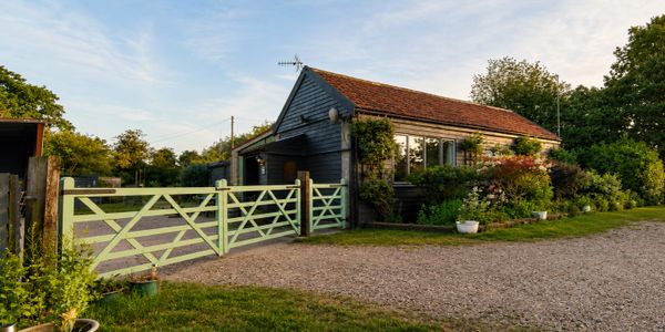 A charming country house with a green wooden gate and lush garden.