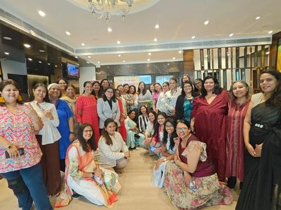 A large group of women posing together indoors, smiling.