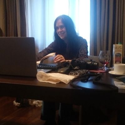 Mujer sonriente trabajando en una laptop en una mesa con varios objetos.