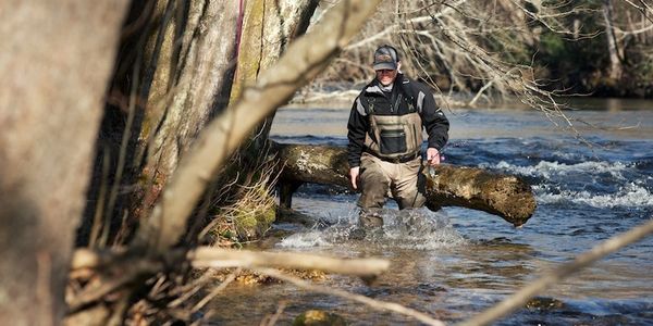 Fly fishing wading in river in Vermont