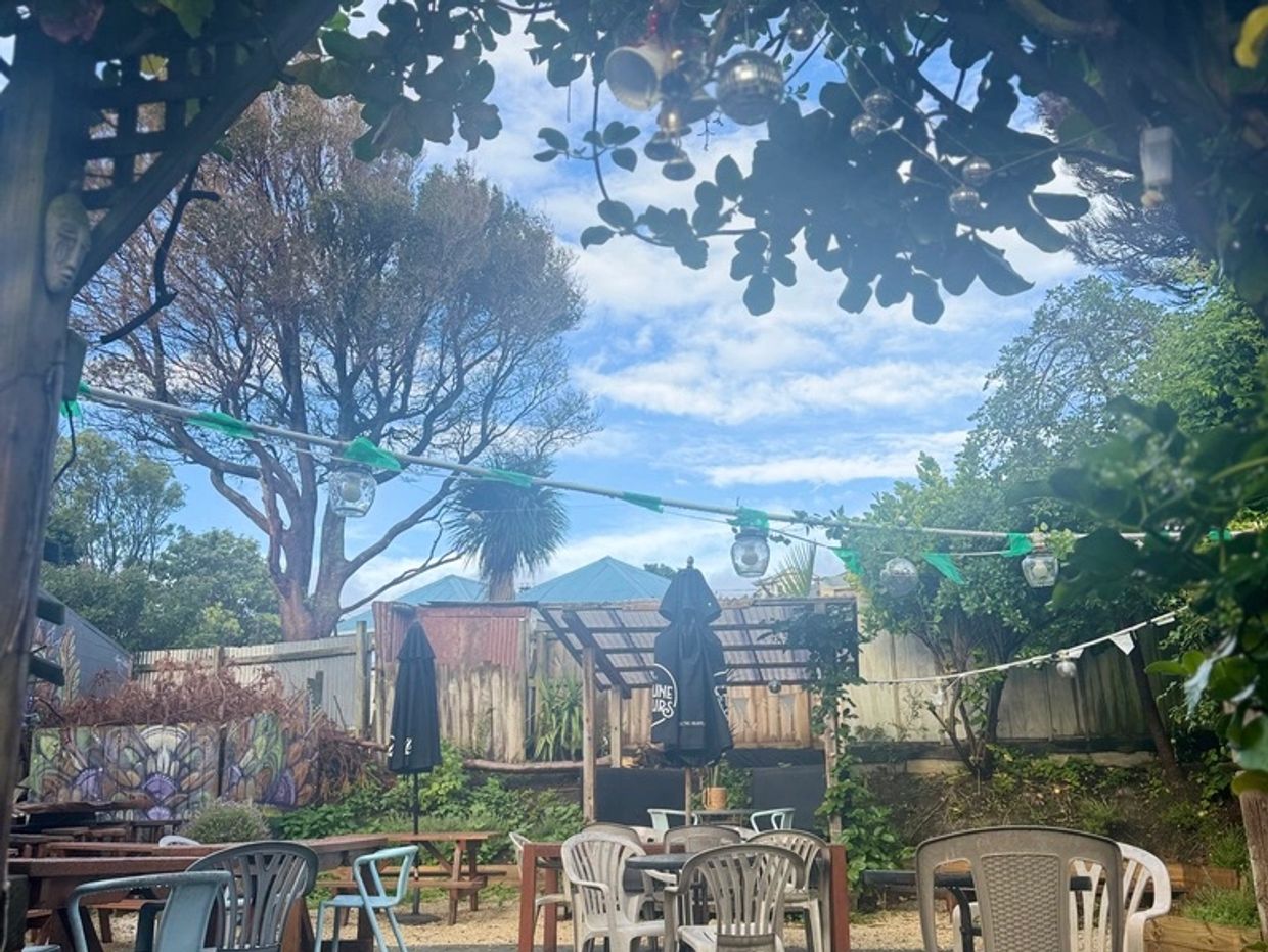 Empty outdoor seating area with trees and blue sky.
