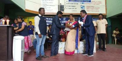 People exchanging gifts on stage during a school event.