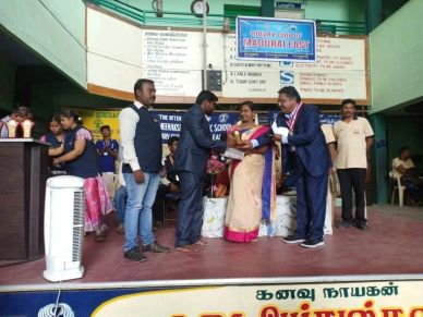 People exchanging gifts on stage during a school event.