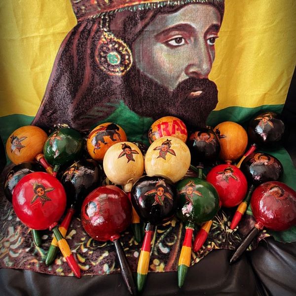Colorful maracas with Rastafarian-themed designs in front of a Rastafarian portrait.