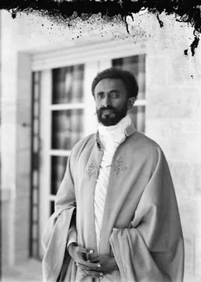 Black and white portrait of a man in traditional attire standing confidently.