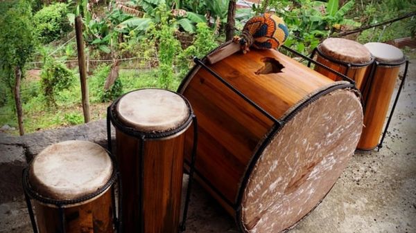 Traditional wooden drums arranged outdoors with a forest background.