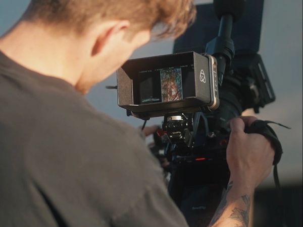 Person filming with a professional camera and monitor.