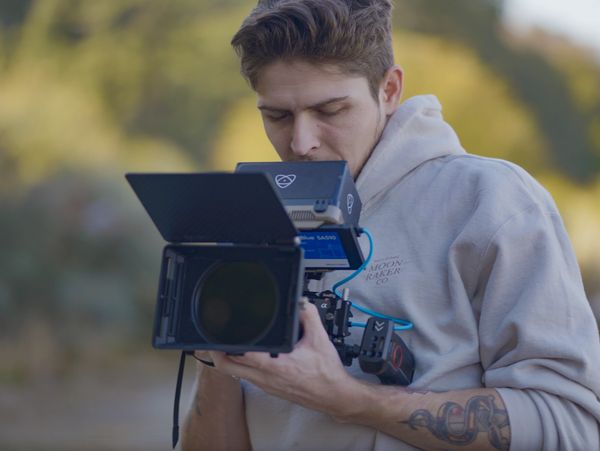 Young man filming with a professional camera outdoors.
