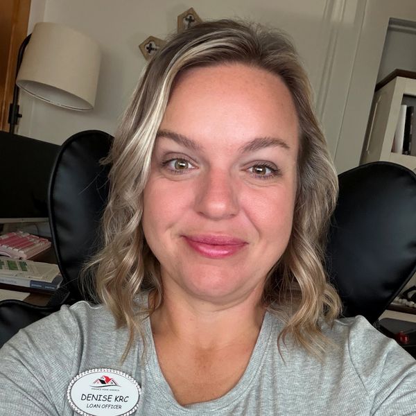 Smiling woman with curly blonde hair and a name tag.