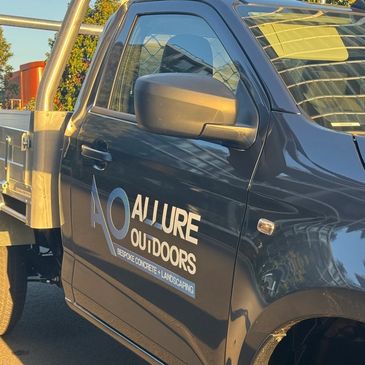 Black pickup truck with Allure Outdoors branding for concrete and landscaping.