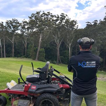 Man standing next to a Toro 2000 HDX lawn mower on a green field.
