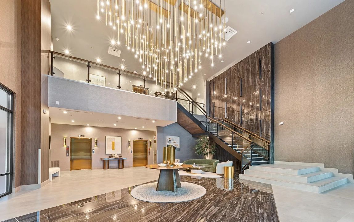 A modern hotel lobby with a grand chandelier and elevators.