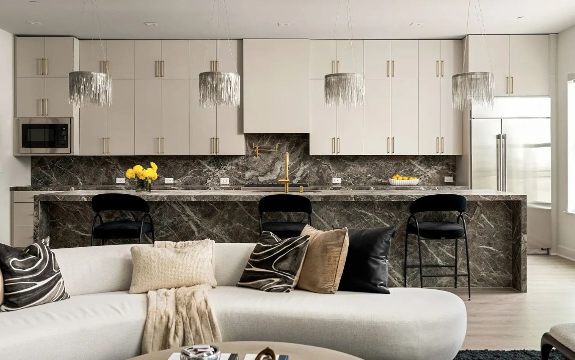 Modern kitchen with marble island and chic lighting.