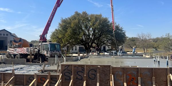 Concrete pouring at a residential construction site under clear blue skies.