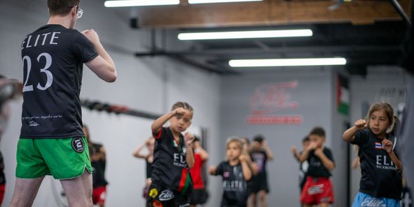 Kids training in martial arts under instructor guidance in a gym.