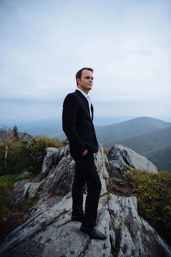 Ryan McKinny from The Crucible stands on a rocky outcrop.