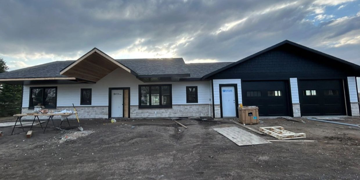 Newly constructed modern house with black and white exterior under cloudy sky.