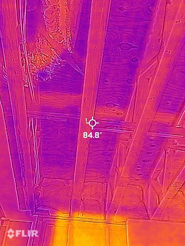 Thermal image of a ceiling with exposed wooden beams showing temperature variations.
