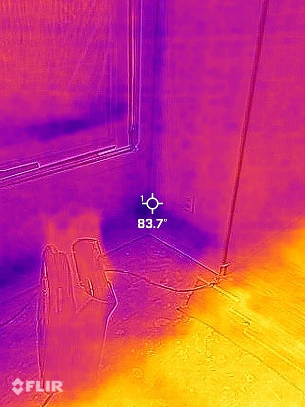Thermal image showing heat variations near a window and floor area with a temperature of 83.7°F.