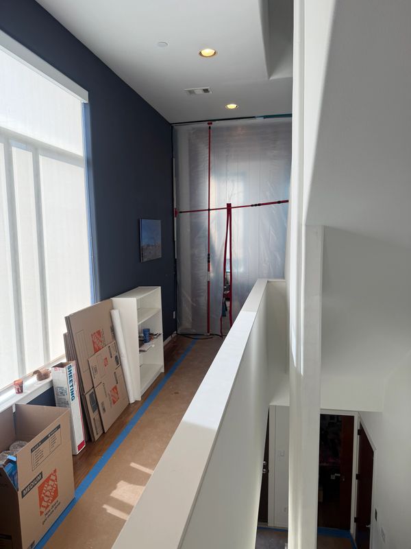Hallway under renovation with protective plastic and moving boxes.