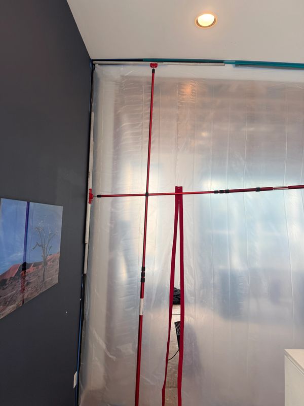 Temporary plastic barrier with red support poles in a room.
