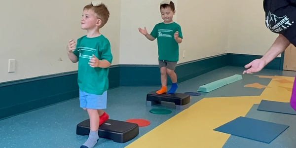Two boys stepping on platforms during a playful indoor activity.