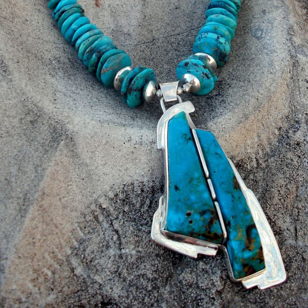 Turquoise and silver beaded necklace with a large pendant.