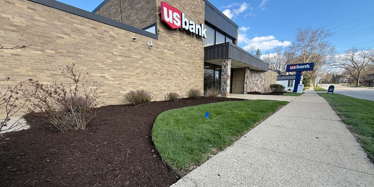 US Bank building with manicured lawn and clear blue sky.