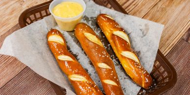 Fresh baked pretzel stick served with cheese sauce