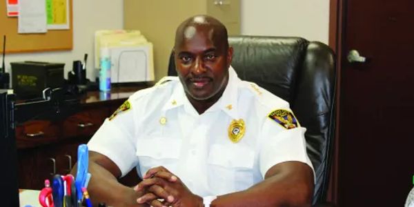 Police officer sitting confidently at his desk in uniform.