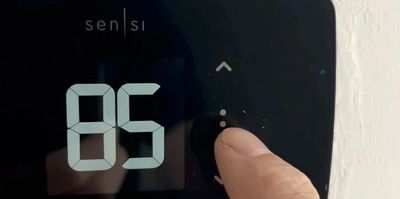finger tapping on a smart thermostat