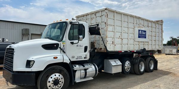A white commercial truck with a large container attached, parked outdoors.