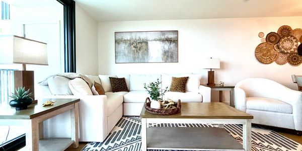 Bright living room with white furniture and wooden accents.