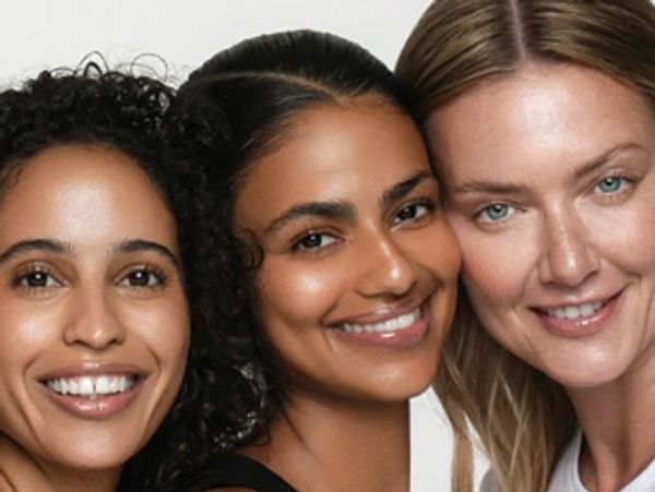 Three smiling women close together, showcasing diverse beauty.