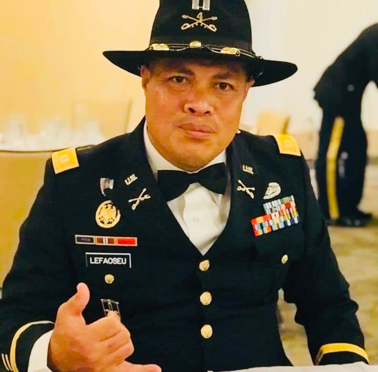 Man in military dress uniform making a hand gesture.
