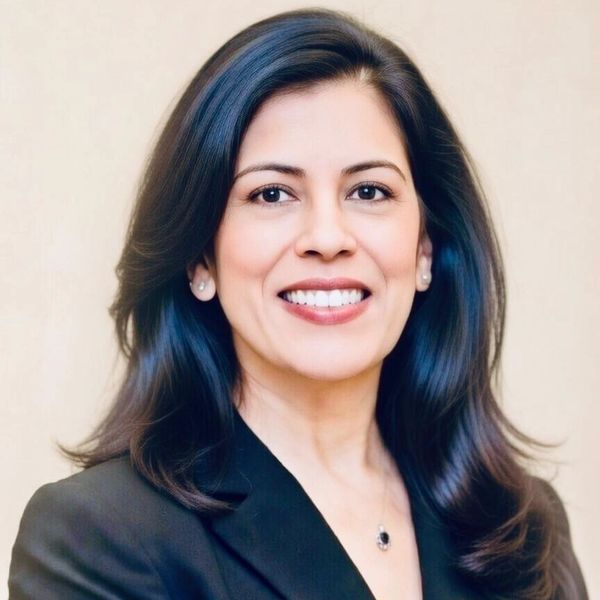 Professional woman smiling confidently with dark hair and business attire.