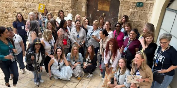 Large group of diverse women posing together outdoors.