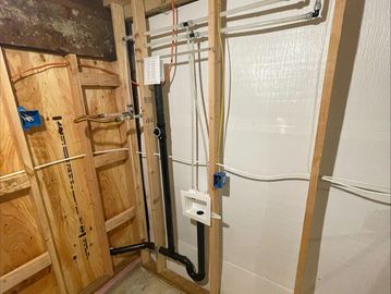 New plumbing installation in a wooden framed basement wall.