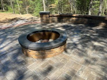 Outdoor stone fire pit in a paved patio area.