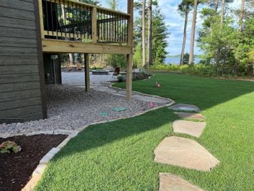 Backyard with stepping stones and a deck overlooking a lake.