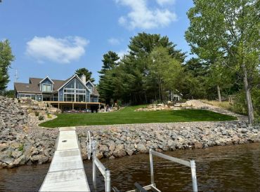 Lakefront house with dock and green yard.