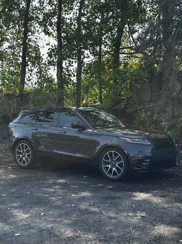 Sleek black SUV parked near trees on a sunny day.