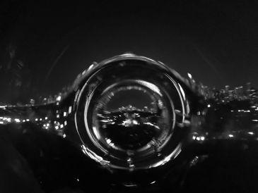 A distorted black-and-white cityscape through a circular lens effect.