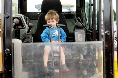 Child in excavator touch a truck