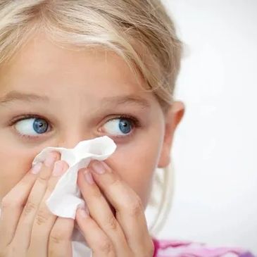 Picture of a young girl blowing her nose.