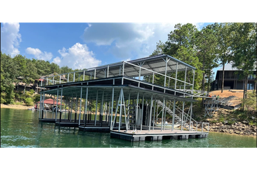 A two-story metal boat dock on a lake beside a wooded shore.